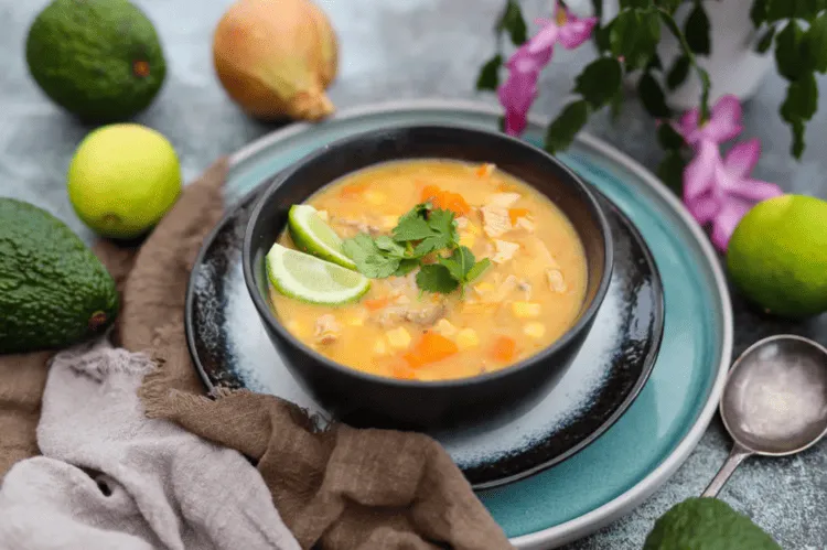 This image shows food blogging tips reflecting food styling and food photography. This is an example image of a bowl of soup orange, with black plates and green accent ingredients.
